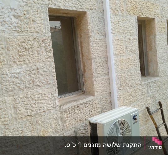 יחידת מיזוג אוויר מותקנת על קיר אבן חיצוני